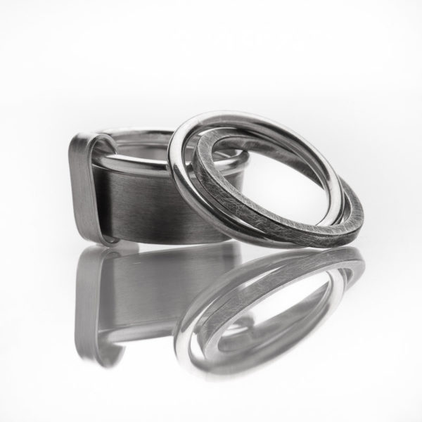 Double-bagues en argent, mat et oxydé. Grand modèle avec un anneau fil rond et une bague plate, et petit modèle avec deux anneaux (fil rond et carré)